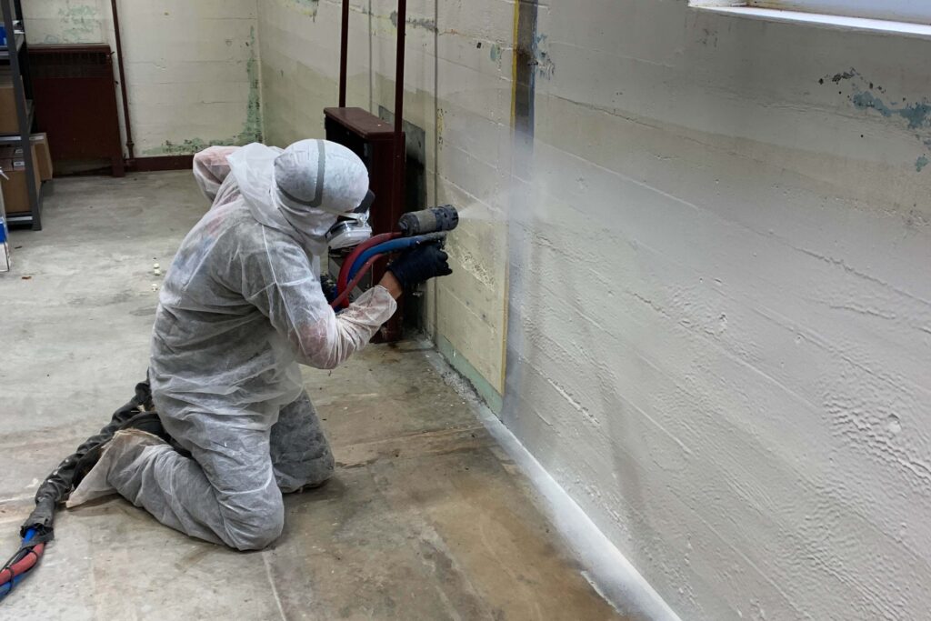 Polyurea coating being applied by ArmorGuard to the basement walls of a home.