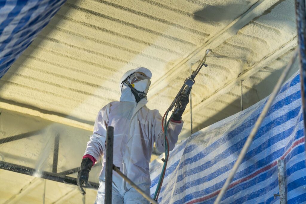 Spray foam insulation being installed by ArmorGuard to the ceiling of a pole barn garage.