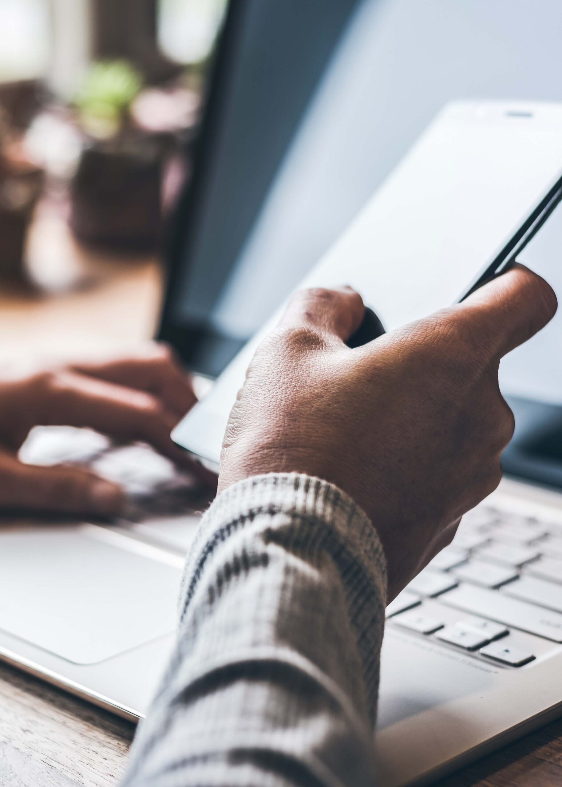 Person using their phone and computer to contact ArmorGuard about their spray foam insulation and coatings services.